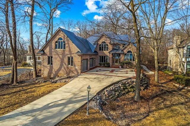 36082 N Beach Rd, Oconomowoc, WI 53066 - view of front of home with brick siding, driveway, a garage, and metal roof