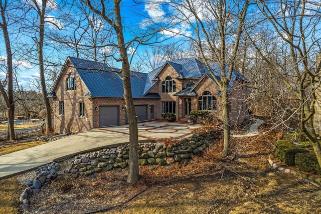 36082 N Beach Rd, Oconomowoc, WI 53066 - view of front facade featuring driveway, a standing seam roof, brick siding, metal roof, and a garage