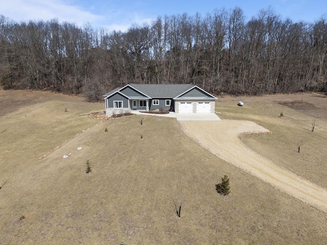 W4668 Reetz Rd, Princeton, WI 54968 - view of front facade with dirt driveway, a garage, a wooded view, and a front lawn