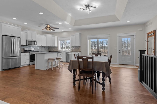 W4668 Reetz Rd, Princeton, WI 54968 - dining room featuring recessed lighting, dark wood-type flooring, ceiling fan, baseboards, and a tray ceiling