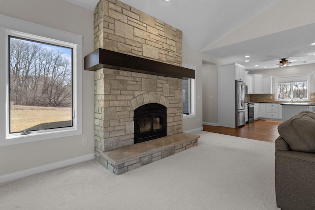 W4668 Reetz Rd, Princeton, WI 54968 - living area with carpet flooring, ceiling fan, baseboards, a stone fireplace, and lofted ceiling