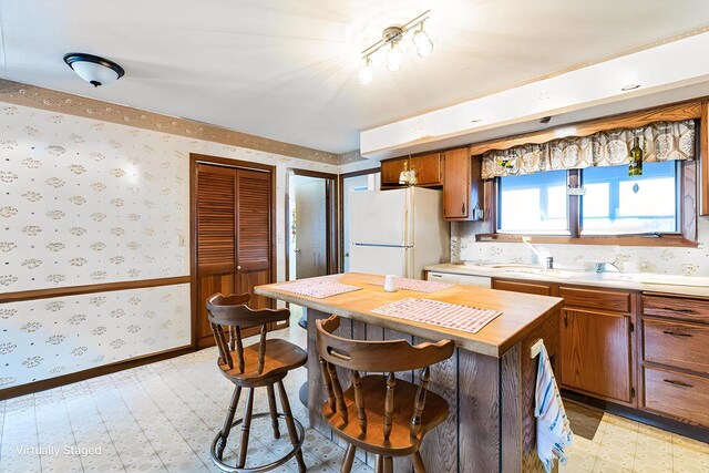 W3736 Oak St, Montello, WI 53949 - kitchen with white appliances, baseboards, wallpapered walls, brown cabinets, and a sink