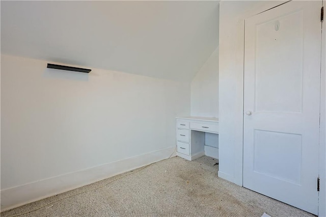 unfurnished bedroom featuring light carpet, baseboards, and lofted ceiling