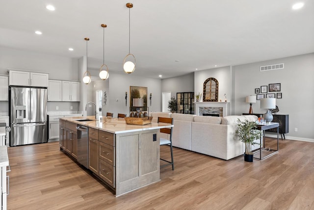 W214N4987 Casey Ct, Menomonee Falls, WI 53051 - kitchen with appliances with stainless steel finishes, a kitchen breakfast bar, recessed lighting, light wood-style floors, and an island with sink