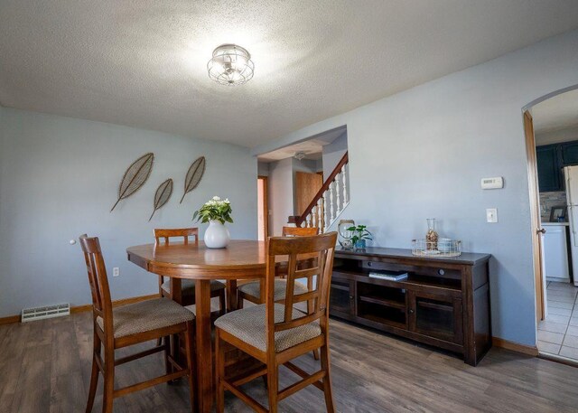 102 Highland St, Belmont, WI 53510 - dining room featuring stairway, a textured ceiling, visible vents, arched walkways, and wood finished floors