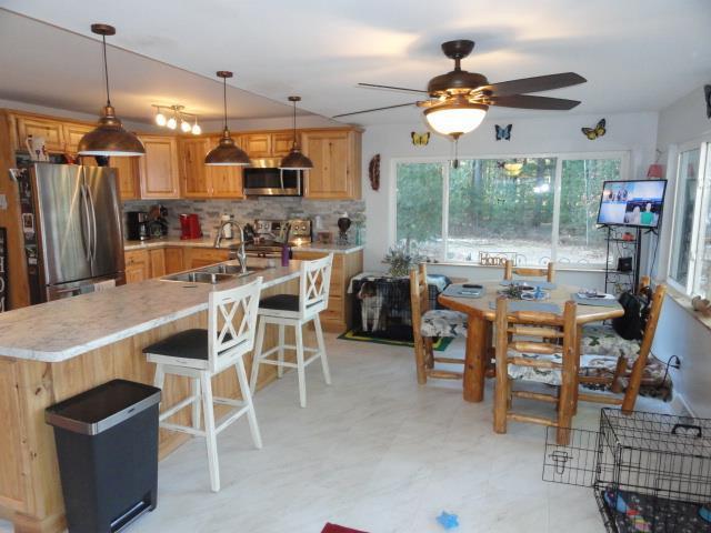 kitchen featuring light countertops, a sink, backsplash, a ceiling fan, and appliances with stainless steel finishes
