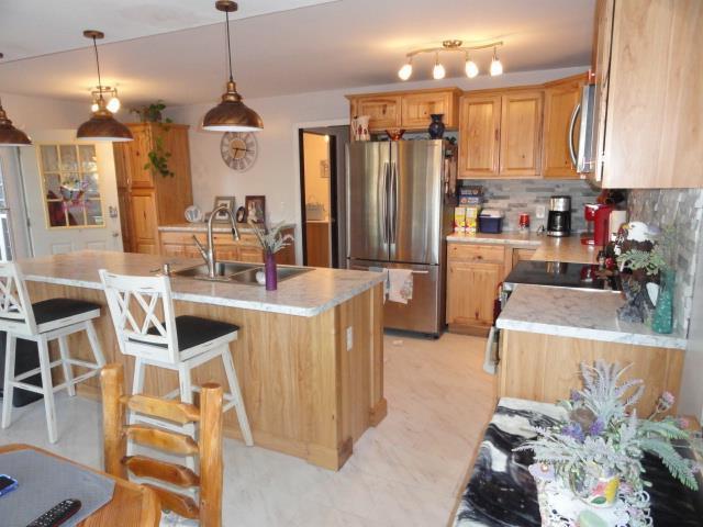 kitchen featuring light countertops, a kitchen breakfast bar, appliances with stainless steel finishes, a sink, and backsplash
