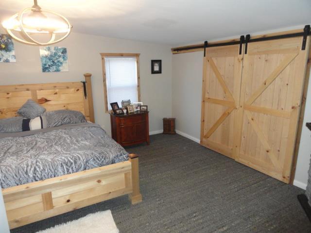 bedroom with baseboards, vaulted ceiling, and a barn door