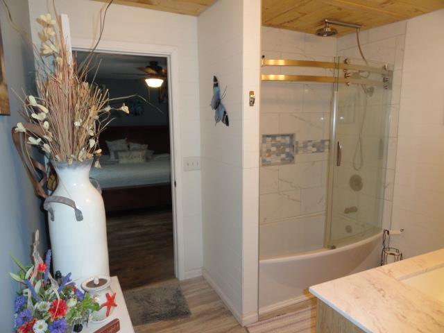 bathroom with tub / shower combination, wooden ceiling, wood finished floors, and ensuite bathroom