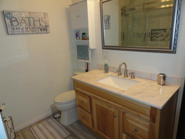 full bathroom featuring toilet, a stall shower, vanity, and wood finished floors