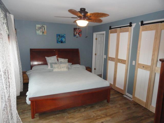 bedroom featuring a barn door, wood finished floors, and a ceiling fan