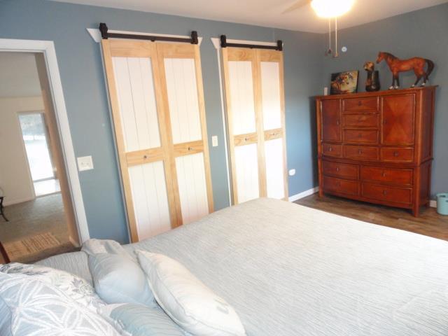 bedroom with a barn door, wood finished floors, and a ceiling fan