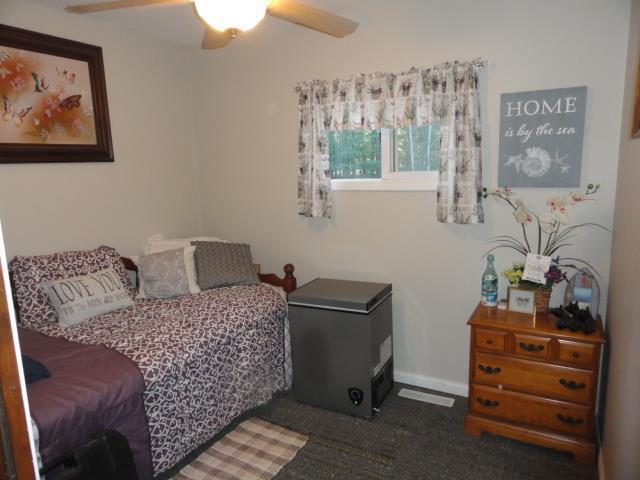 bedroom with ceiling fan and refrigerator