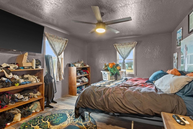 7760 State Highway 186, Arpin, WI 54410 - bedroom with a ceiling fan, a textured wall, a textured ceiling, and wood finished floors