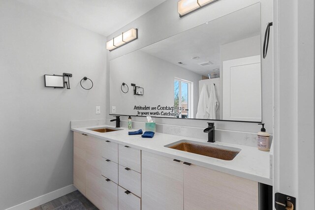bathroom featuring baseboards, double vanity, visible vents, and a sink