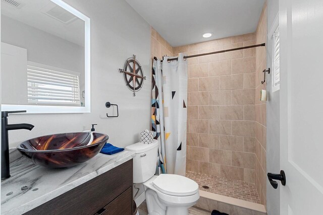 bathroom featuring toilet, vanity, visible vents, and a shower stall