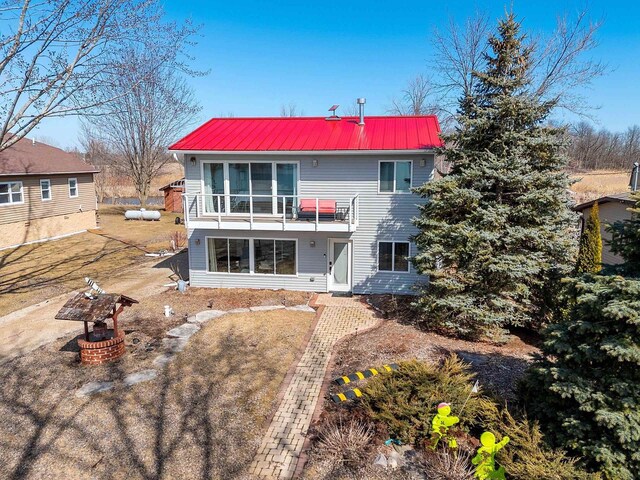 back of property with a balcony and metal roof