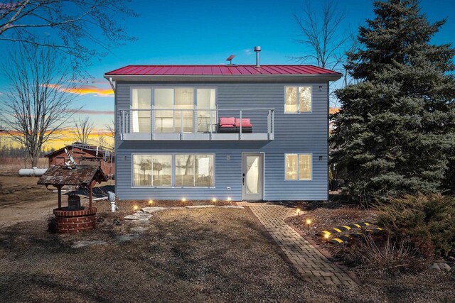 back of property with a balcony, metal roof, and a standing seam roof