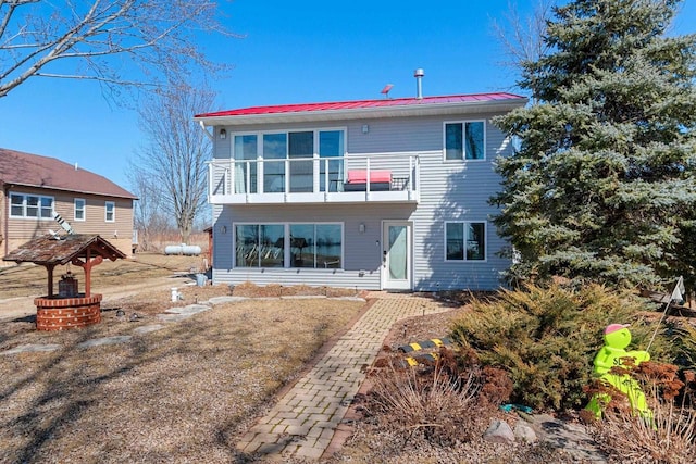 rear view of house featuring a balcony and metal roof