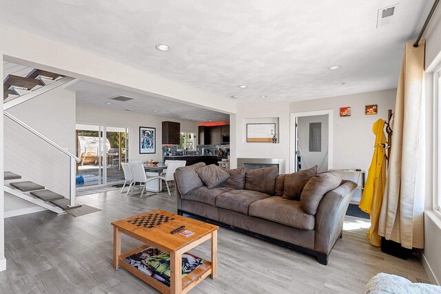living room featuring stairway, light wood finished floors, and visible vents