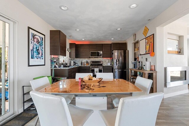 dining space featuring baseboards, recessed lighting, and light wood finished floors