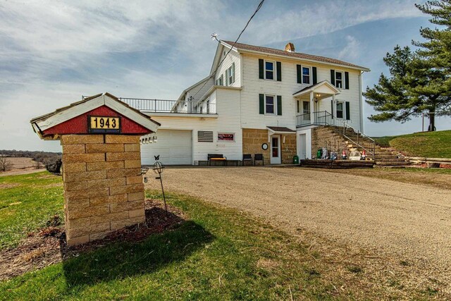 1943 State Road 11, South Wayne, WI 53587 - view of front of property with stairway, dirt driveway, a chimney, stone siding, and a garage