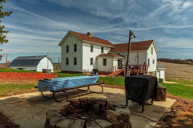 1943 State Road 11, South Wayne, WI 53587 - back of house featuring central air condition unit, a wooden deck, an outdoor structure, a patio, and an outdoor fire pit