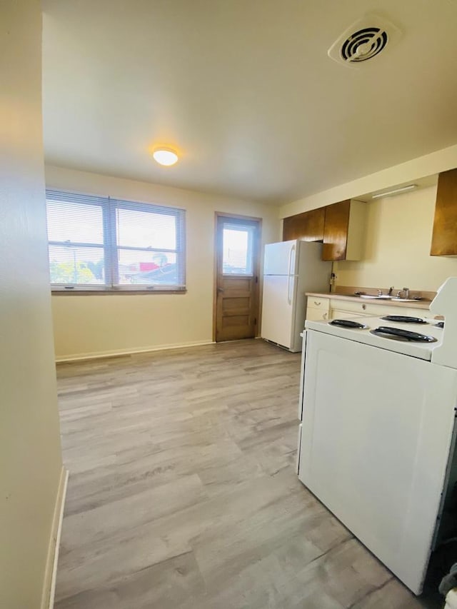 clothes washing area with a sink, visible vents, baseboards, and light wood-type flooring