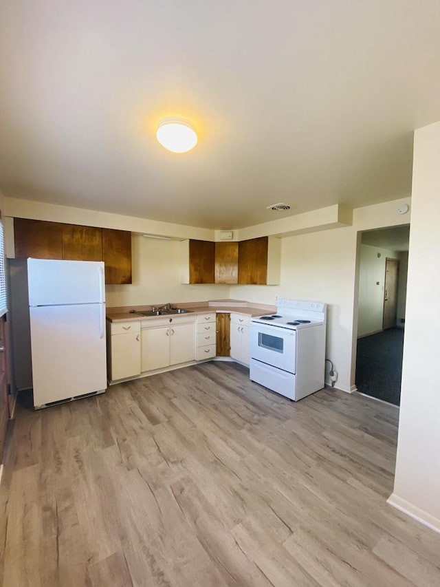 kitchen with white cabinets, visible vents, light wood-type flooring, and white appliances