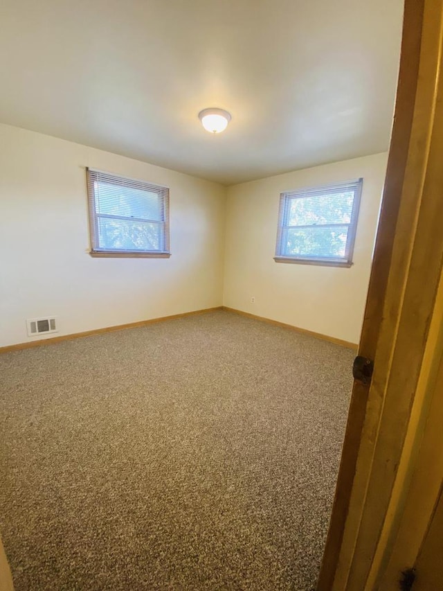 spare room featuring baseboards, visible vents, and carpet