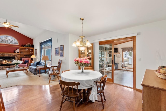 N8891 Gladstone Beach Rd, Fond Du Lac, WI 54937 - dining area featuring vaulted ceiling, plenty of natural light, a brick fireplace, and light wood-style flooring