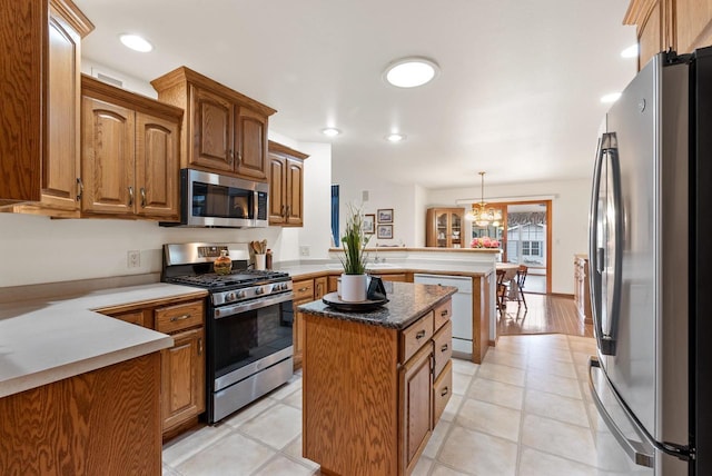 N8891 Gladstone Beach Rd, Fond Du Lac, WI 54937 - kitchen with a peninsula, a kitchen island, brown cabinets, decorative light fixtures, and stainless steel appliances
