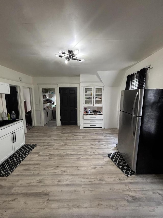 kitchen with white cabinets, light wood-style flooring, and freestanding refrigerator