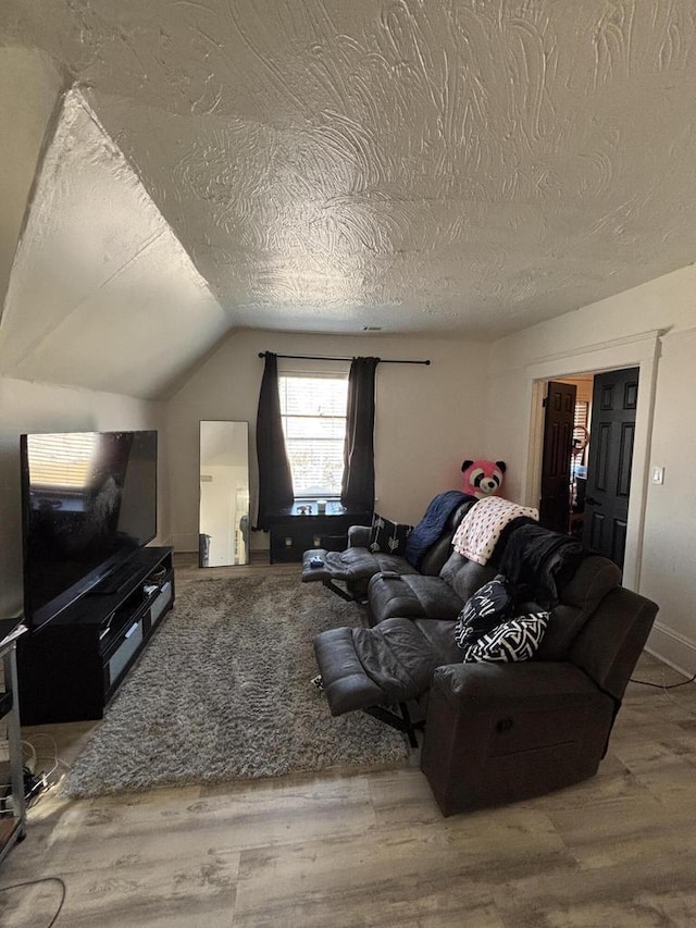 living room featuring vaulted ceiling, wood finished floors, and a textured ceiling