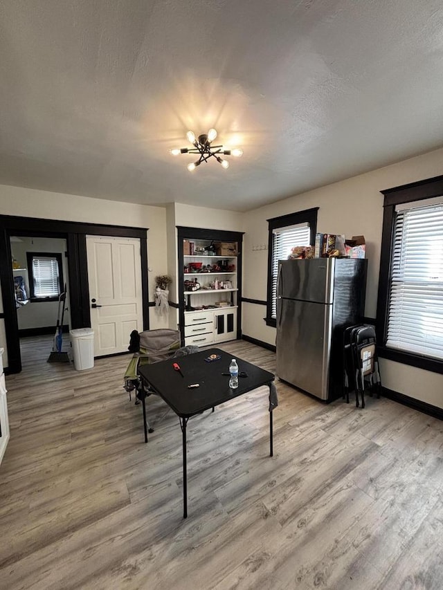 playroom with a notable chandelier, baseboards, light wood finished floors, and a textured ceiling