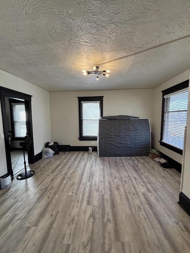 interior space with baseboards, light wood finished floors, and a textured ceiling