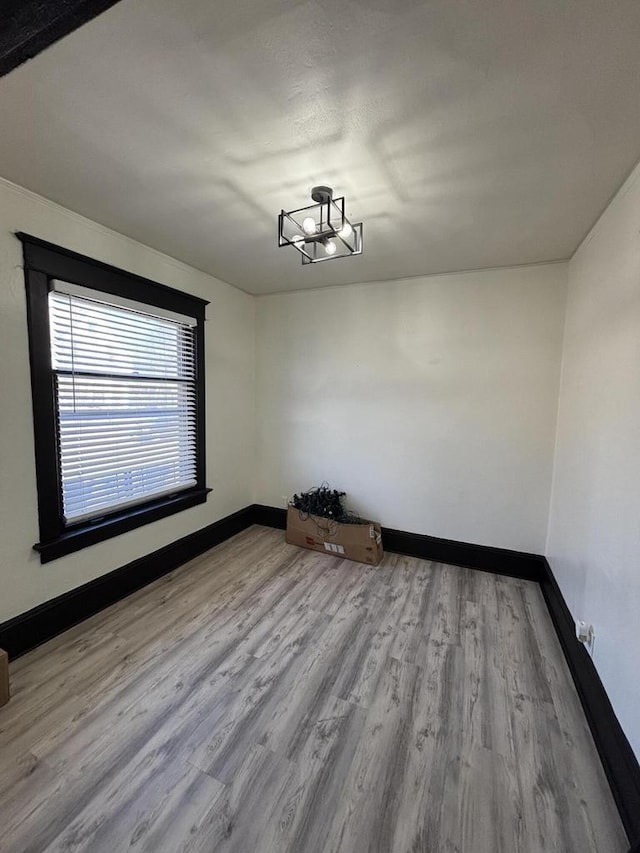 spare room featuring baseboards, wood finished floors, and a notable chandelier