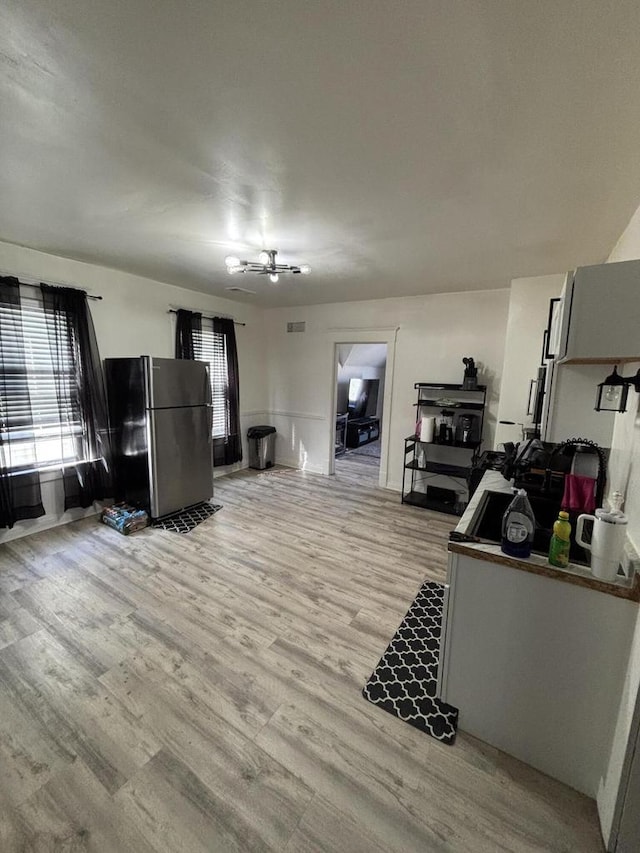 living area with a notable chandelier, light wood-style floors, and visible vents
