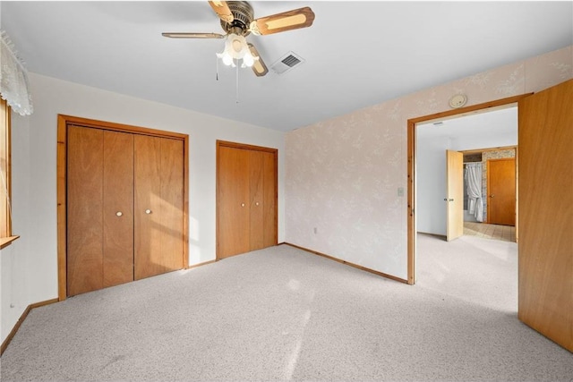 8375 N Bass Lake Rd, Danbury, WI 54830 - unfurnished bedroom with visible vents, two closets, baseboards, ceiling fan, and carpet floors