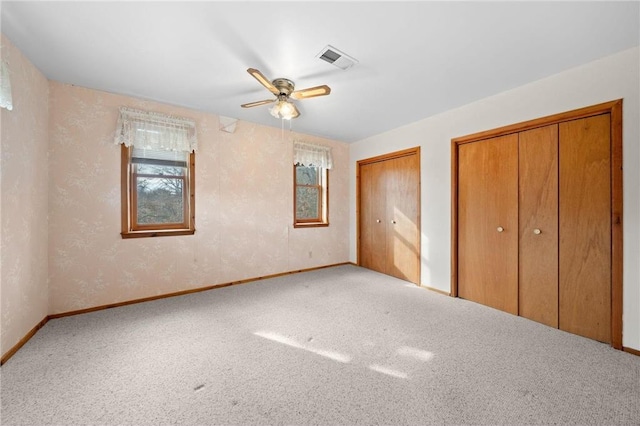 8375 N Bass Lake Rd, Danbury, WI 54830 - unfurnished bedroom featuring baseboards, two closets, carpet, and a ceiling fan