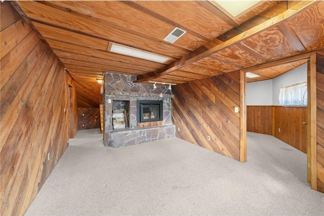 8375 N Bass Lake Rd, Danbury, WI 54830 - unfurnished living room featuring visible vents, wood walls, carpet, and a stone fireplace