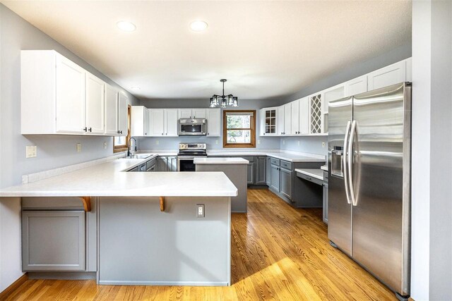 836 Westwind Dr, Black River Falls, WI 54615 - kitchen with a chandelier, light countertops, a sink, a peninsula, and appliances with stainless steel finishes