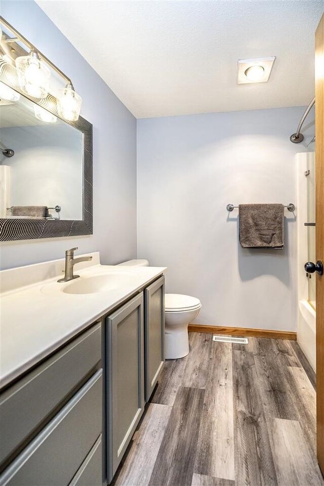 836 Westwind Dr, Black River Falls, WI 54615 - full bathroom featuring toilet, visible vents, wood finished floors, shower / bath combination, and vanity