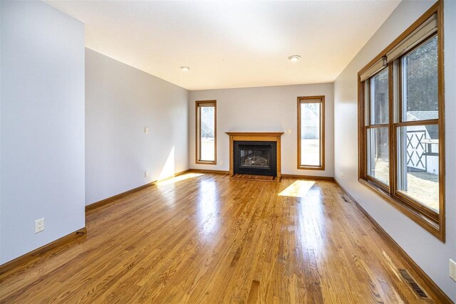 836 Westwind Dr, Black River Falls, WI 54615 - unfurnished living room featuring a fireplace with flush hearth, baseboards, wood finished floors, and visible vents