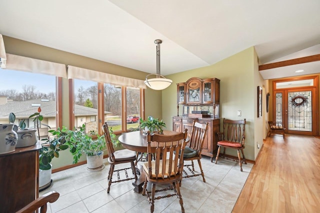 dining space with baseboards, lofted ceiling, and light tile patterned floors