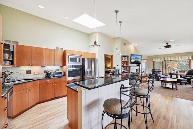 kitchen featuring a breakfast bar, dark countertops, appliances with stainless steel finishes, a sink, and open floor plan
