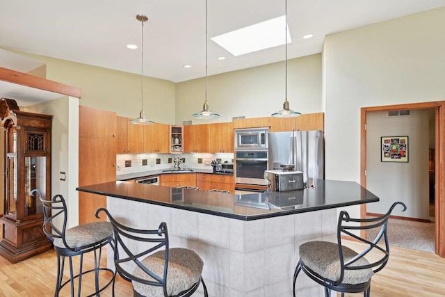 kitchen featuring brown cabinets, dark countertops, a skylight, and stainless steel appliances