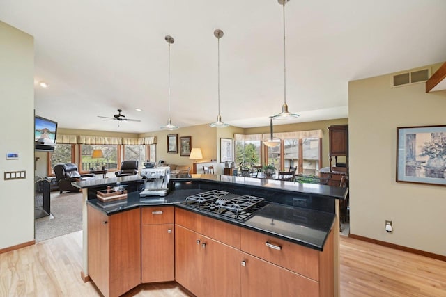 kitchen featuring a kitchen island, black gas cooktop, open floor plan, light wood-type flooring, and visible vents