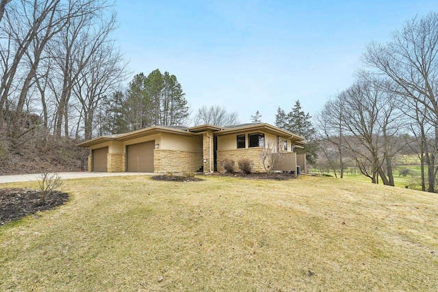 view of front of property with stone siding, driveway, a front lawn, and an attached garage