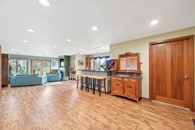 kitchen with a kitchen breakfast bar, recessed lighting, light wood-type flooring, a peninsula, and brown cabinetry